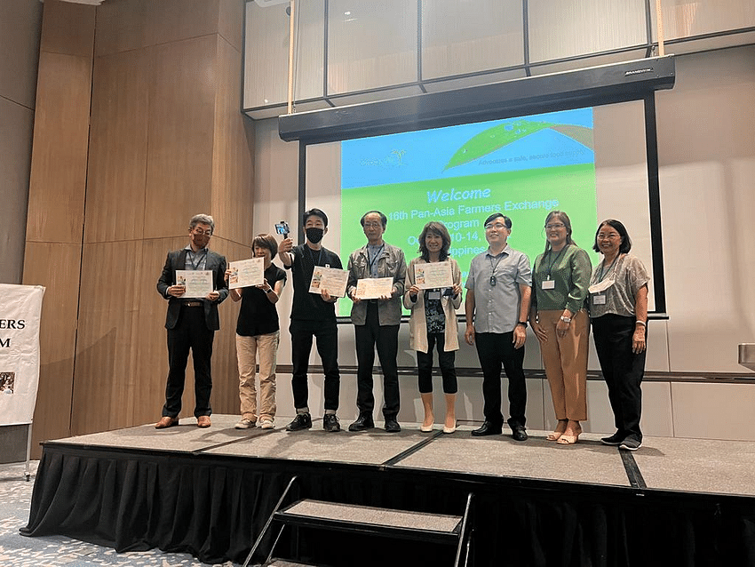 Participants pose together on stage with their participation certificates.